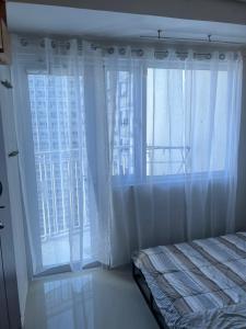 a bedroom with a bed and a large window at 39th Flr Condo Unit with View in Manila