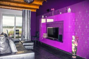 a living room with a purple wall with a tv at Apartamento con estilo y acogedor in Sant Mateu