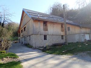 Um velho celeiro com um poste à frente. em Gîte le creux de vennes 