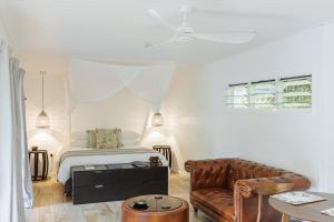 a white bedroom with a bed and a couch at mist at Cape Tribulation in Cape Tribulation