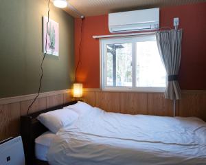 美瑛町にあるC HOTEL 美瑛白金 - Biei Shiroganeのベッドルーム(白いベッド1台、窓付)
