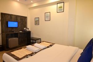 a bedroom with a bed with a tv on the wall at Blue Pearl A Boutique Hotel in Goa