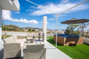 a patio with a hot tub and an umbrella at Sunny Villa in Faliraki