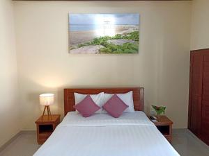 Un dormitorio con una cama con almohadas rosas y blancas. en Manda Homestay, en Sanur