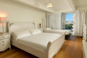 a white bedroom with two beds and a window at Artis Appartamento in Rimini