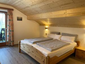 a bed in a room with a wooden ceiling at Zum Bergbauer in Mittenwald