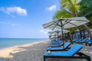 een rij stoelen en parasols op een strand bij Anja Beach Resort & Spa in Phu Quoc