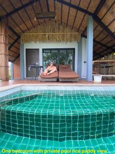 a woman sitting on a couch next to a swimming pool at Rongna Villas in Ko Yao Noi