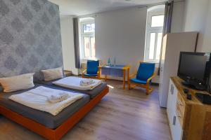 a room with a bed and two chairs and a television at Ryde & Hyde Budget Hotel in Dresden