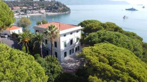 uma casa numa colina com árvores e água em Villa Doria 16Pax Waterfront by VILLASRETREATS em Portovenere
