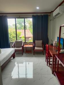 um quarto com uma cama, uma mesa e cadeiras em Dokchampa Hotel em Vang Vieng