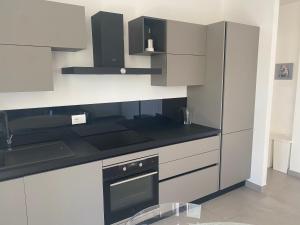 una cocina con armarios blancos y electrodomésticos negros en Venere Apartament, en Tirrenia