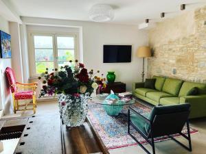 CorteViva Boutique Cottage في SantʼEgidio: غرفة معيشة مع أريكة خضراء و مزهرية من الزهور