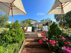 a patio with two umbrellas and some flowers at CorteViva Boutique Cottage in SantʼEgidio