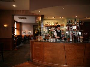 a man standing behind a bar in a restaurant at The Royal Highland Hotel in Inverness