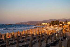 - une plage avec de nombreux parasols et l'océan dans l'établissement MichELe Luxury apartments by Smaris Collection, à Mália