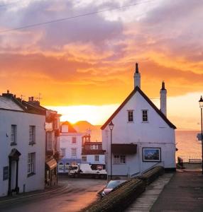 um edifício branco com um pôr-do-sol ao fundo em Seabreeze -modern spacious house with great garden em Lyme Regis