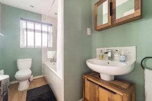 ein Badezimmer mit einem Waschbecken, einem WC und einem Spiegel in der Unterkunft 3 bedroom house with modern interior, close to the Etihad stadium in Manchester