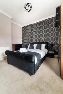 a bedroom with a large bed with a black leather couch at 3 bedroom house with modern interior, close to the Etihad stadium in Manchester