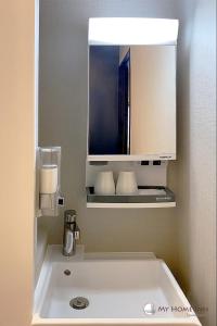 a bathroom with a sink and a mirror at My Home Inn Izumisano in Izumi-Sano