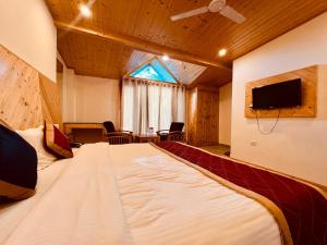 Cette chambre comprend un grand lit et une télévision. dans l'établissement Manali Castle - Wonder Hill, à Manali