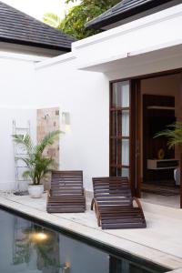 two chairs on a patio next to a swimming pool at Villa Manis La Bora in Seminyak in Seminyak