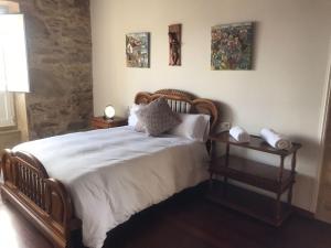 um quarto com uma cama de madeira e uma mesa lateral em Casa de Romaxe em Muros
