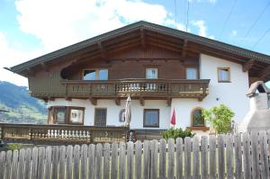 une maison avec une clôture en bois devant elle dans l'établissement Haus hart im Zillertal 6 personen, à Hart im Zillertal