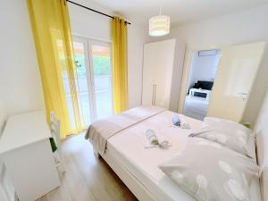 a bedroom with a white bed with towels on it at Evergreen & Pinky Apartments close to the Beach in Rab