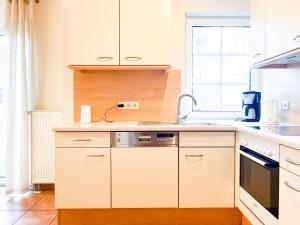 una cocina con armarios blancos y fregadero en Reethus Natalie, en Zingst