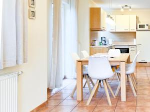 cocina y comedor con mesa de madera y sillas blancas en Reethus Natalie, en Zingst