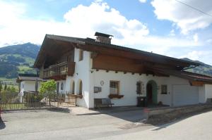 Cette petite maison blanche dispose d'une terrasse couverte et d'un balcon. dans l'établissement Haus hart im Zillertal 6 personen, à Hart im Zillertal