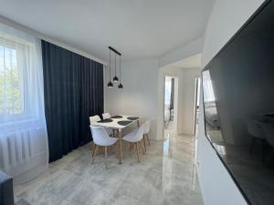 a white dining room with a table and chairs at Apartament Słoneczny in Frombork
