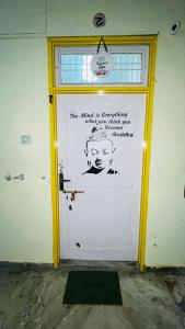 eine weiße Tür mit einem Schild drauf in der Unterkunft The Little Peaceful Cozy Home ! Aadhish Homestay in Varanasi + 3 Fotos