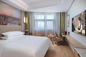 Cette chambre comprend un grand lit blanc et un bureau. dans l'établissement 汝州维也纳酒店, à Yüchow