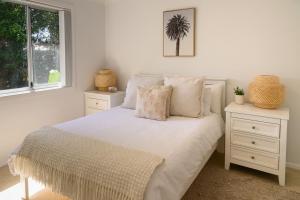 a white bedroom with a bed and two night stands at Sandcastles in Barrack Point