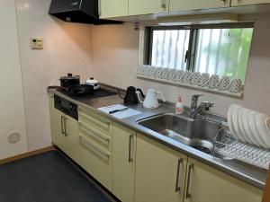 cocina con fregadero, fogones y ventana en 4 Bedrooms, 3 Toilets, 2 bathtubs, 2 car parking , 140 Square meter big Entire house close to Makuhari messe , Disneyland, Airports and Tokyo for 18 guests, en Narashino