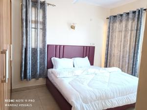 um quarto com uma cama com lençóis brancos e almofadas em Elegant furnished rooms and apartments near mall em Mombaça
