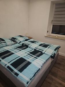 a bed with a blue and black blanket on it at Ferienwohnung Grimma in Grimma