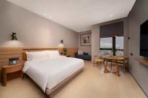 a bedroom with a large white bed and a table at SSAW Boutique Hotel Hangzhou Chengjun in Hangzhou