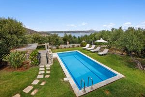 einen Pool in einem Garten mit Gras und Bäumen in der Unterkunft Sea view villa Manolis with private pool near the beach in Kalyves