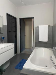 ein Badezimmer mit einer großen weißen Badewanne und einem Waschbecken in der Unterkunft SeaBreeze Guest Suite in Kapstadt + 23 Fotos