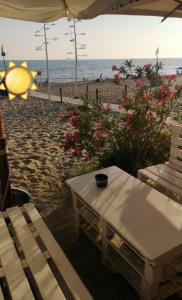 a table and a bench on the beach at La Stella Sea House in Torvaianica