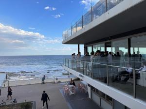 un grupo de personas de pie en un edificio junto al océano en Cosy Merewether Studio - sleeps one en Merewether