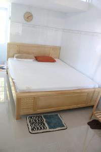 uma cama de madeira num quarto com um relógio na parede em 79/10 Tran Phu House em Can Tho