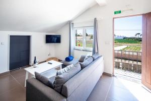 uma sala de estar com um sofá e uma grande janela em Silvercoast Apartments - swimming pool & jacuzzi em Atouguia da Baleia