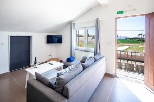 a living room with a couch and a large window at Silvercoast Apartments - swimming pool & jacuzzi in Atouguia da Baleia