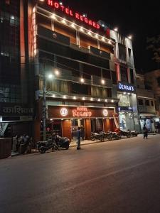 un hombre de pie delante de un hotel por la noche en Hotel Regard en Varanasi