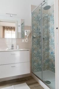 W łazience znajduje się szklana kabina prysznicowa i umywalka. w obiekcie Il Giramondo w Agropoli