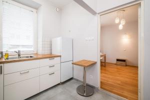 a kitchen with white cabinets and a wooden table at Schindler's Studio WAWELOFTS in Krakow